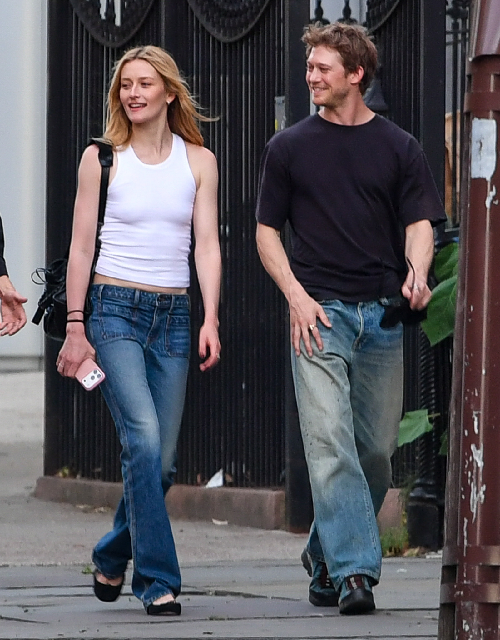 Sarah Pidgeon walks down the street in New York with Joe Alwyn wearing bootcut jeans with black ballet flats and a white tank top.