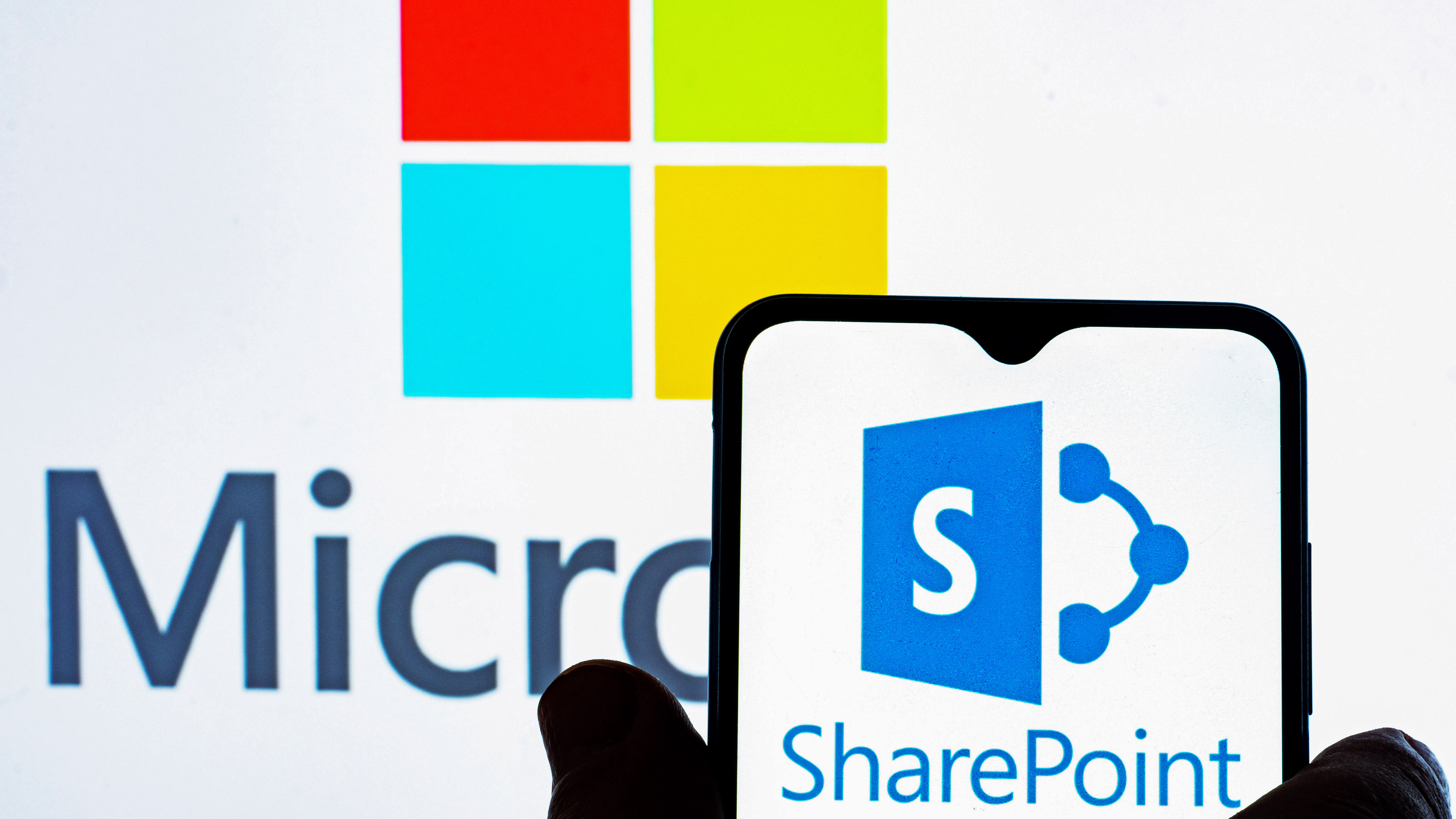 UKRAINE - 2022/01/11: In this photo illustration, the Microsoft SharePoint logo is seen displayed on a smartphone and Microsoft logo in the background. (Photo Illustration by Igor Golovniov/SOPA Images/LightRocket via Getty Images)