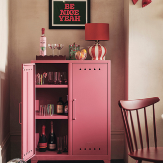 Red striped lamp on top of a pink cocktail cabinet