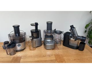 A selection of juicers on wooden surface including the Philips Masticating Juicer, NutriBullet Pro, Sage 3X Bluicer and Hurom H-AA slow juicer