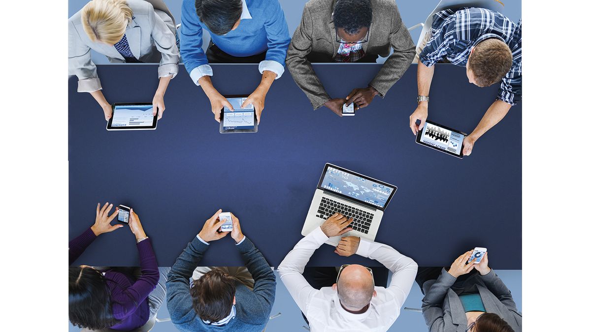 Team meeting around a table with laptop, tablets and smartphones