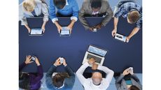 Team meeting around a table with laptop, tablets and smartphones