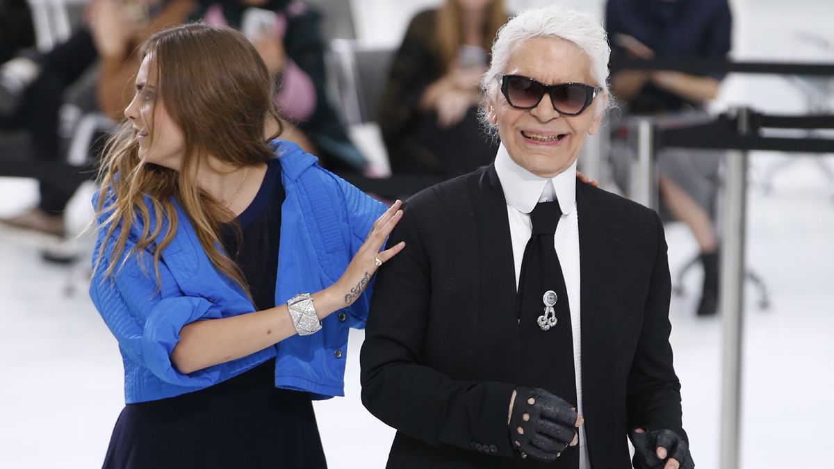 German fashion designer Karl Lagerfeld acknowledges the public along with British model Cara Delevingne at the end of the Chanel 2016 Spring/Summer ready-to-wear collection fashion show, on O