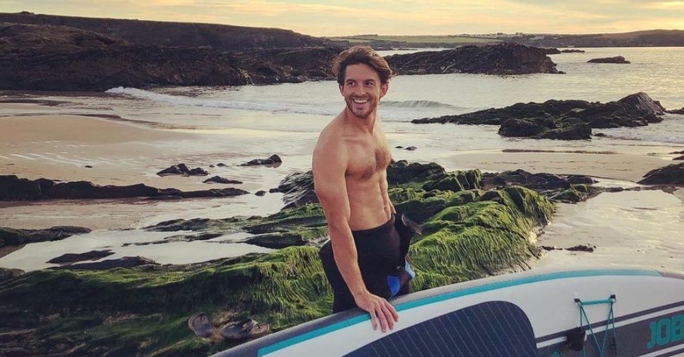 a photo of actor Jonathan Bailey holding a paddleboard