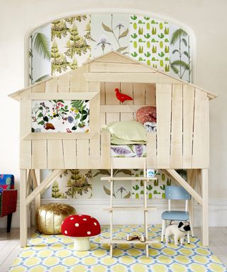 An example of loft bed ideas showing a kids bedroom with a loft bed shaped like a treehouse with plant printed wallpaper behind