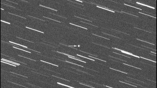 A balck and white image of an asteroid streaking through the stars