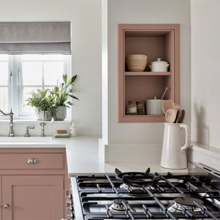 storage shelves built into chimney breast in a pink kitchen