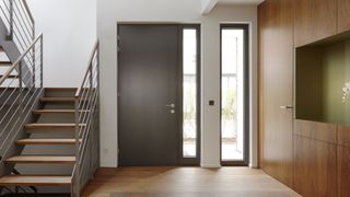 grey front door on inside of home with glass panels and staircase