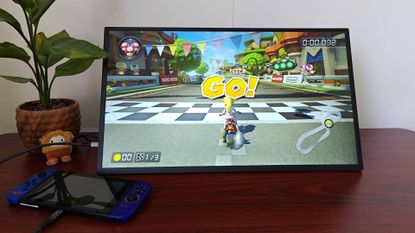 Uperfect Umax 24 portable monitor on desk connected to Nintendo Switch with Mario Kart 8 Deluxe gameplay on screen and Peach at start line.