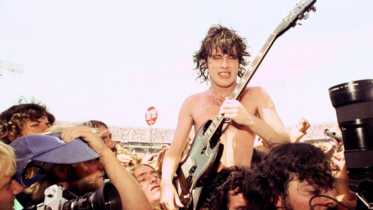 OAKLAND - 1978: L-R Angus Young and Bon Scott of AC/DC get swept away by fans and media at The Oakland Coliseum 1978 in Oakland, California