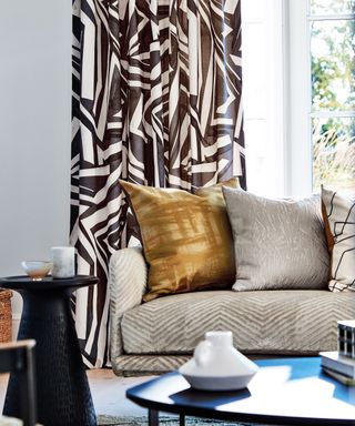 Gray sofa with gold pillow and printed curtains
