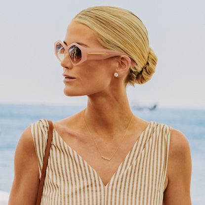 Kitty Spencer turning to the side wearing sunglasses and a striped dress