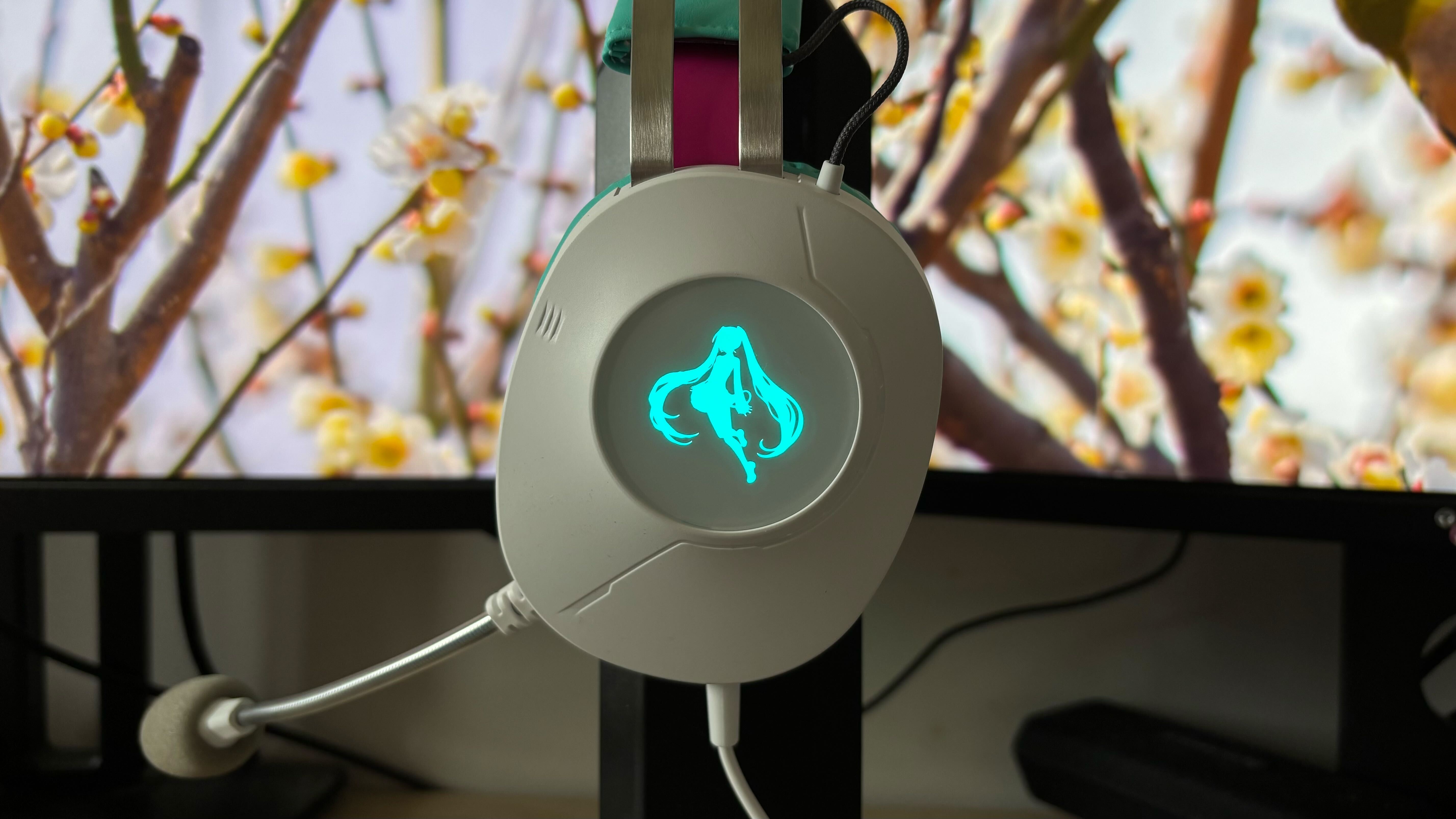 TUF Gaming x Hatsune Miku collaboration headset against floral background on monitors with blue Miku icon light