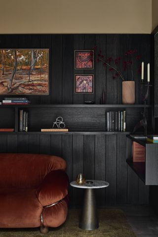 A living room with a red couch and black walls