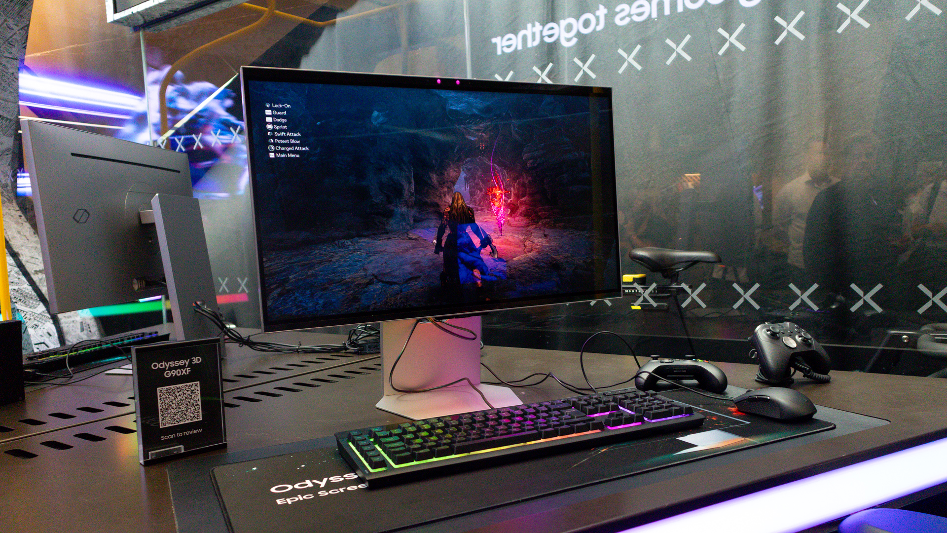 Samsung Odyssey 3D monitor on a desktop with keyboard, Xbox controller and other gaming accessories