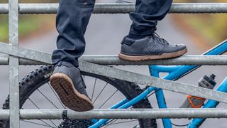 The Five Ten Sleuth DLX shoe being worn by MTB rider while climbing a gate
