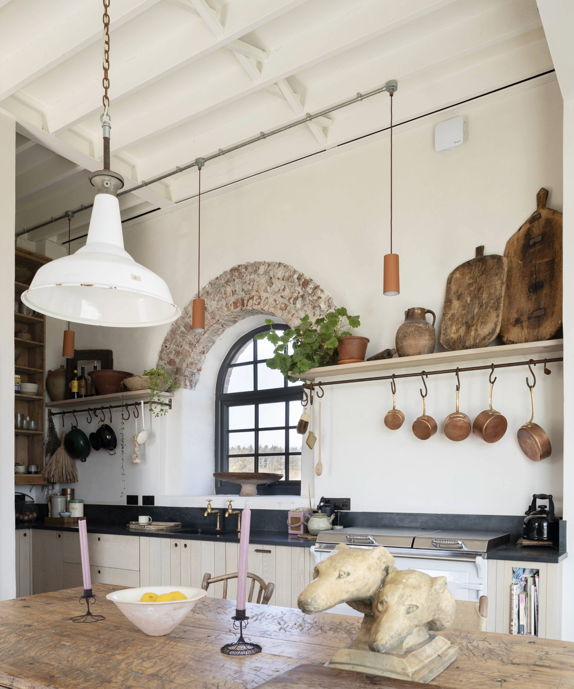 Kitchen with arched window, wooden table, and open shelving 
