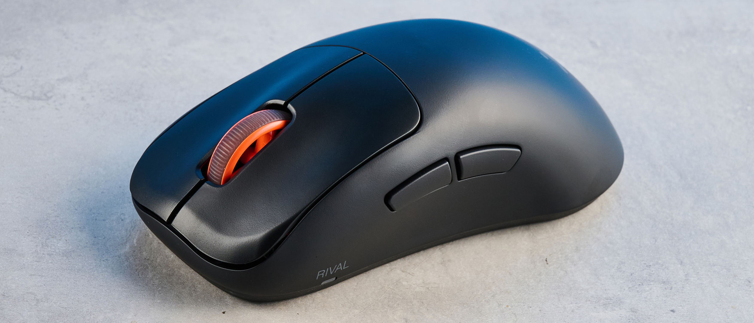 The SteelSeries Rival Pro mouse on a grey stone surface