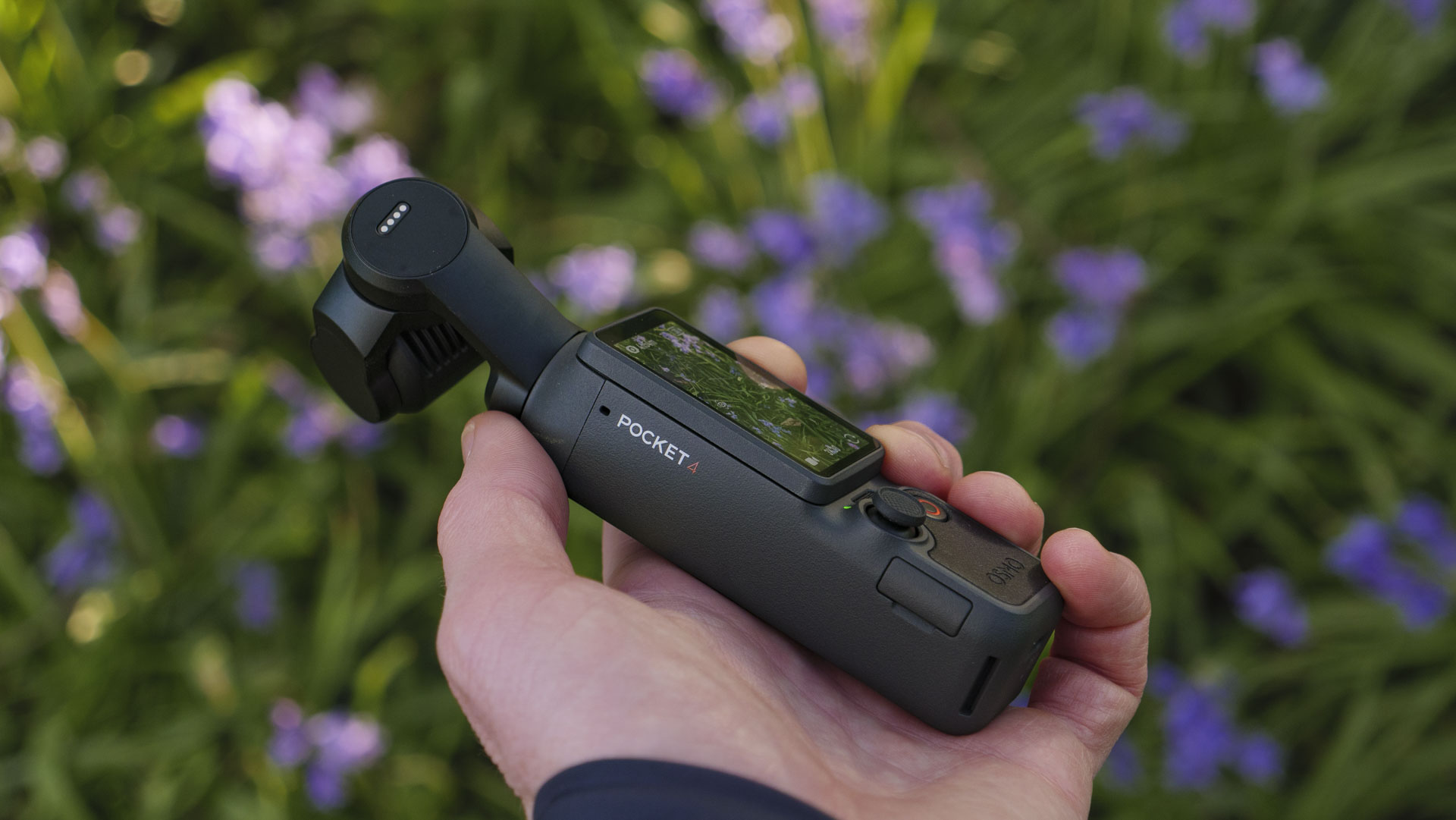 Side profile of the DJI Osmo Pocket 4 vlogging camera with natural background of bluebells