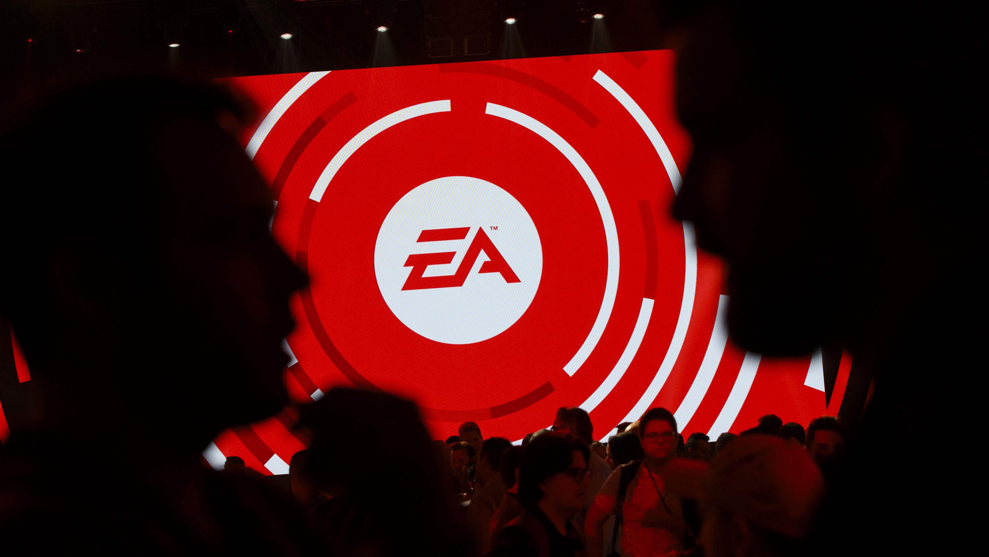 Attendees gather in front of an Electronic Arts Inc. (EA) logo displayed on a screen during the company&#039;s EA Play event ahead of the E3 Electronic Entertainment Expo in Los Angeles, California, U.S., on Saturday, June 10, 2017. EA revealed two new titles along with the annual iterations of the company&#039;s sports games, as well as unveiling the highly anticipated &quot;Star Wars: Battlefront II&quot; open-world multiplayer gameplay. Photographer: Patrick T. Fallon/Bloomberg via Getty Images