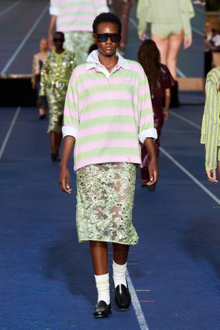 a model walks the Copenhagen Fashion Week runway wearing a pink and green striped polo shirt