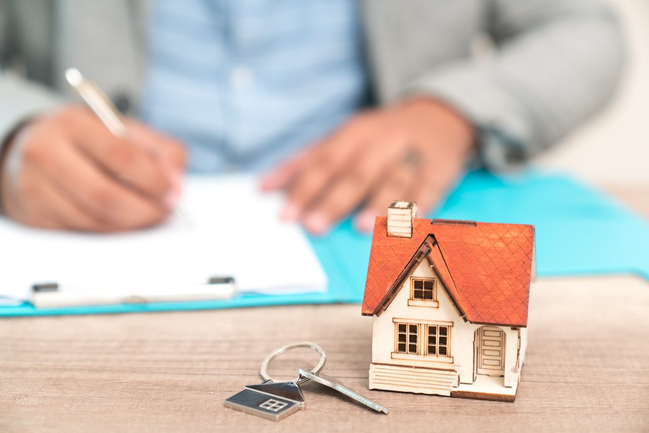 Estate agent with keys and a mini house