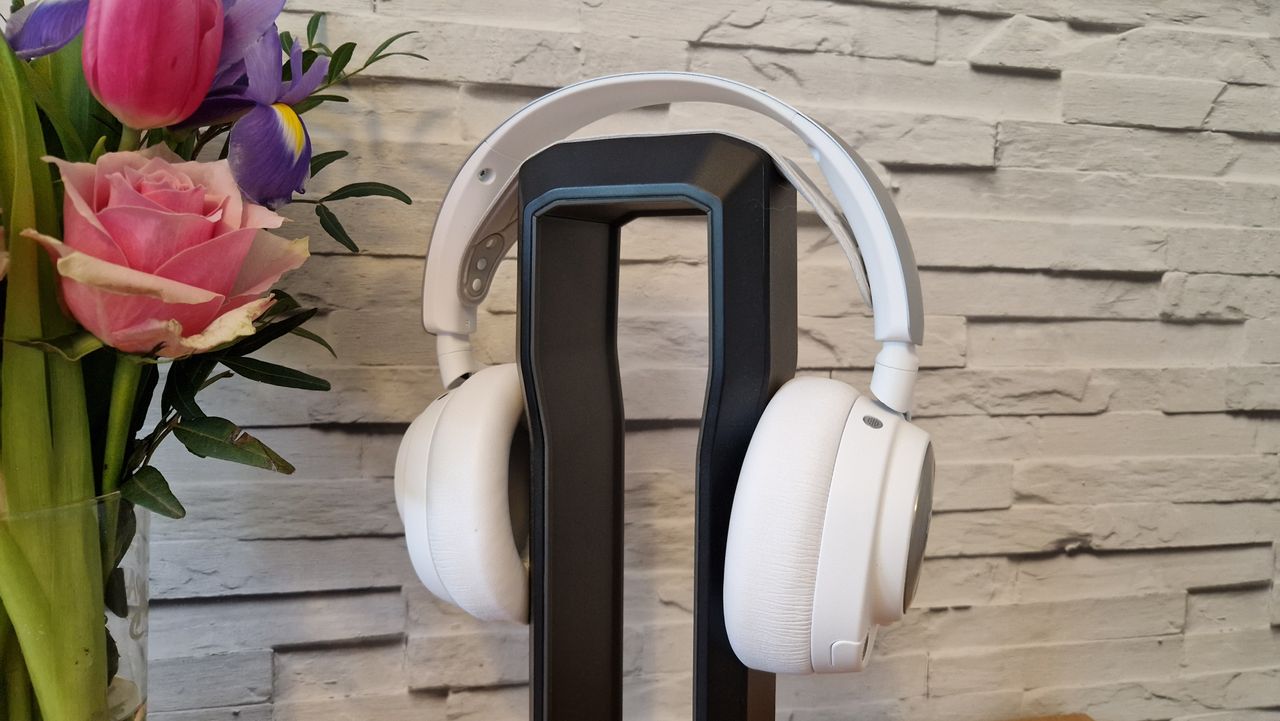 The SteelSeries Arctis Nova Pro Wireless white edition on a headset stand with a white brick background