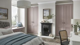 bedroom with blush pink built-in wardrobes, fireplace, large bed and dressing table