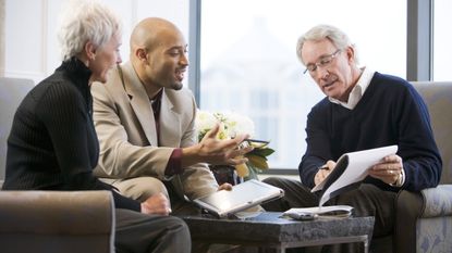 A couple talk with a financial adviser in his office about retirement planning.
