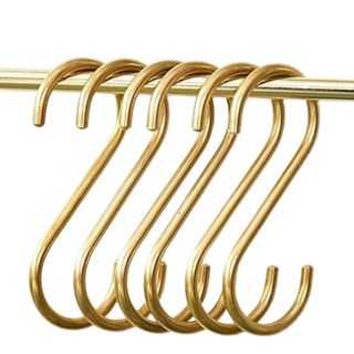 Six S-shaped gold hooks hanging on a gold rail