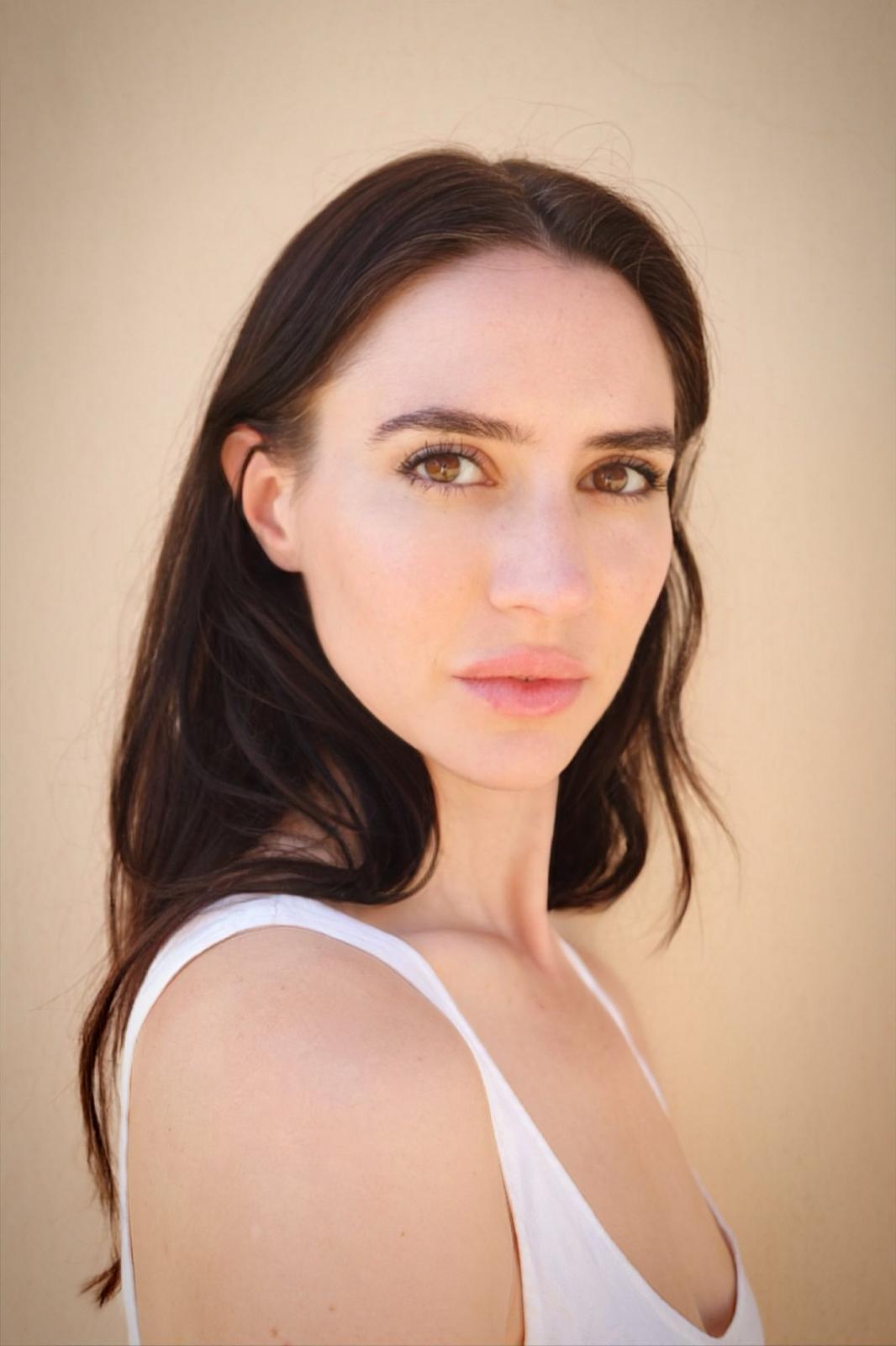 a white woman with dark hair in a white tank top
