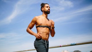 A bare chested runner wearing a chest strap heart rate monitor