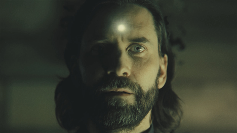 Alan Wake with a glowing bullet hole in his forehead in Alan Wake 2.