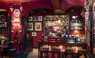 Cranberry red walls, warm wooden accents, and soft lighting complete the atmosphere of the Parlour