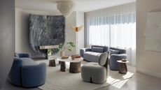 Image of a living room with a cream and light blue color scheme. There is a nesting coffee table in the center of the room with two blue velvet sofa across from each other and a gray accent chair.