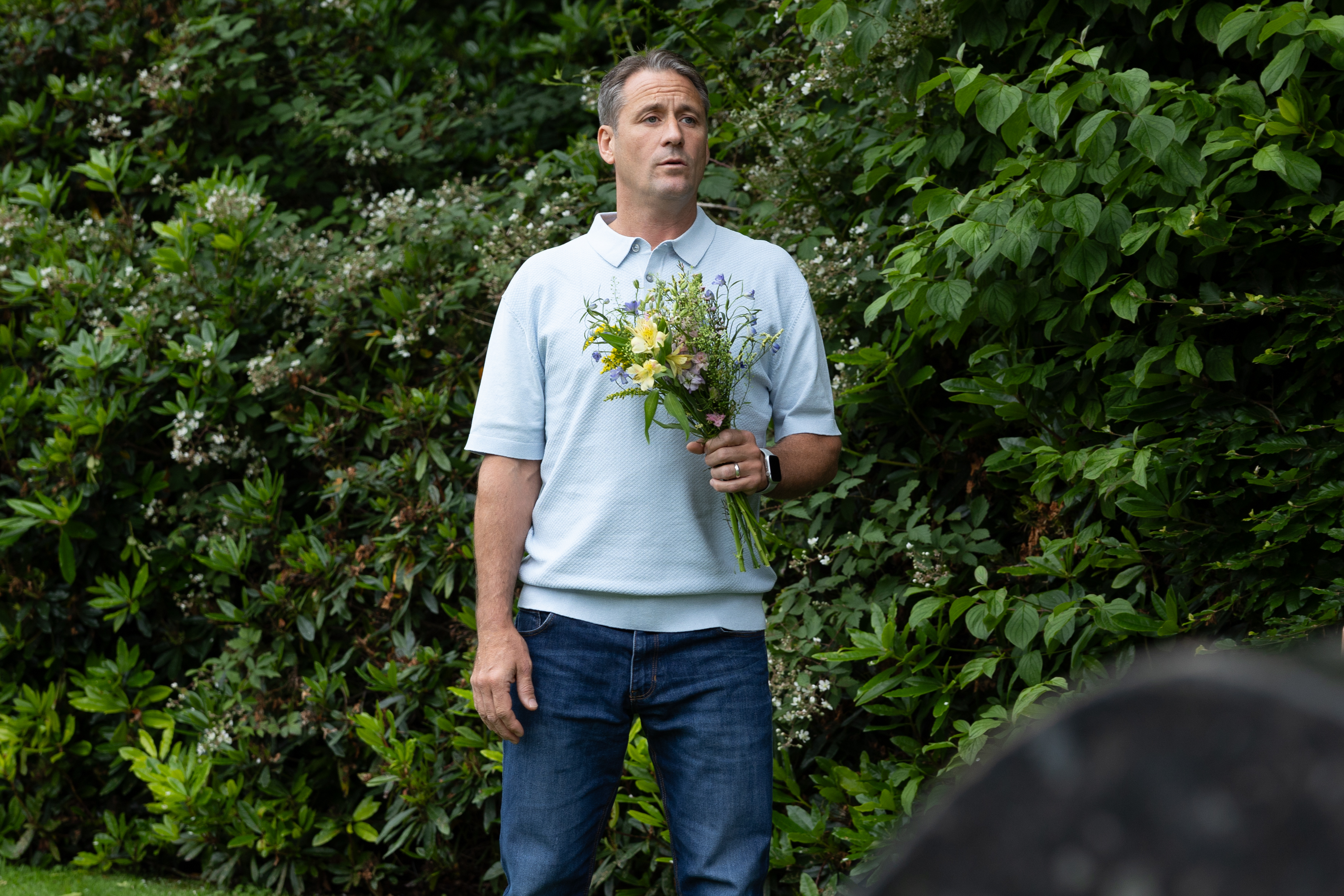 Tony Hutchinson is at the graveyard carrying a bunch of flowers.