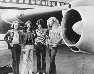 Led Zeppelin standing next to the wing of an airplane