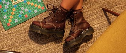 Brown Dr Martens lace up boots next to a scrabble board