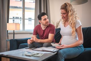 Pregnant couple talking about money at home