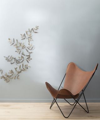A white wall with a vine and a brown lounge chair.