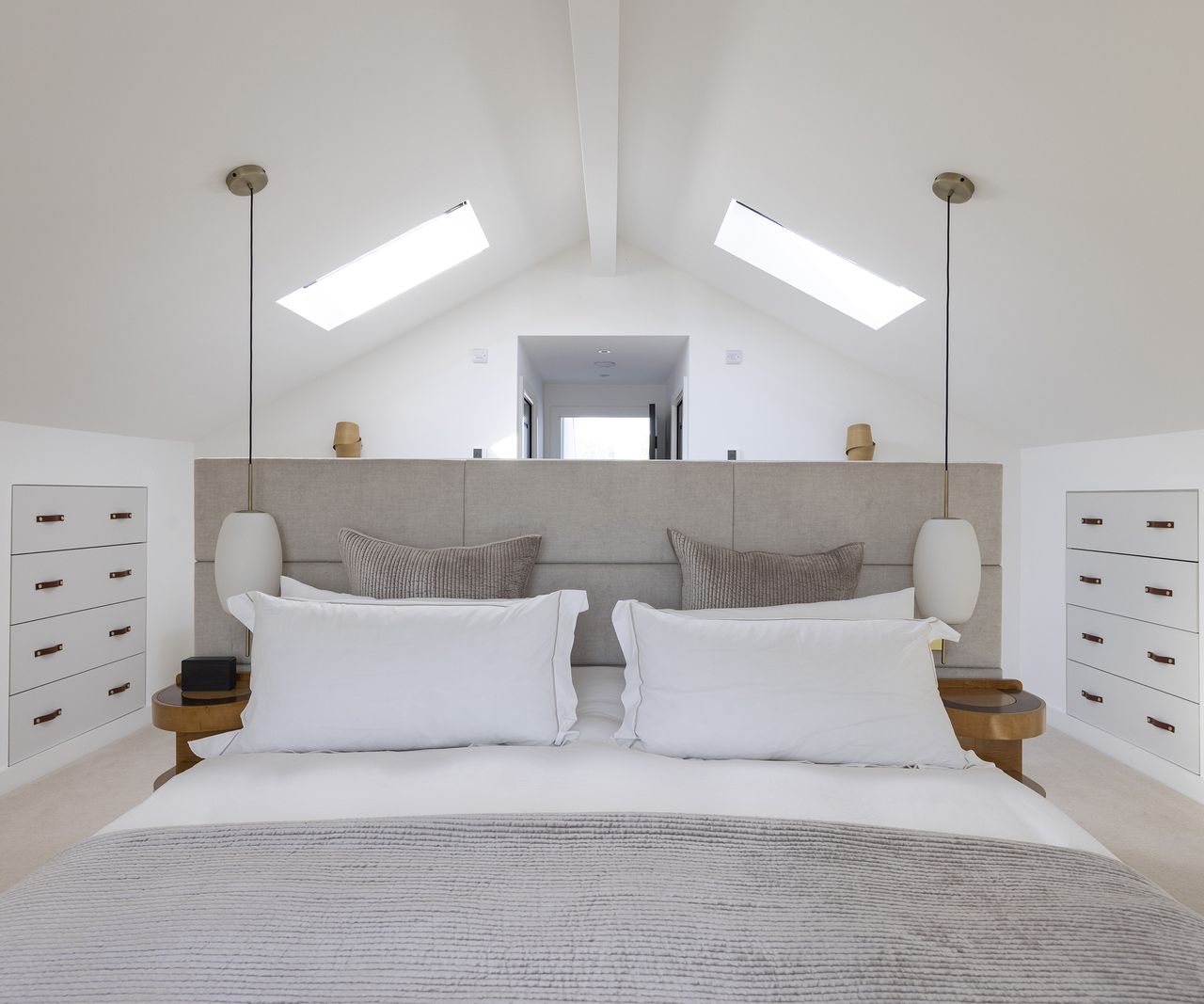 View of a double bed in a loft room with hanging pendant lights