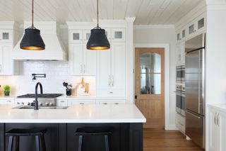 white farmhouse kitchen with black island and rustic metal pendant lights