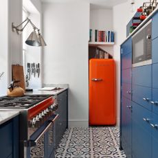 narrow kitchen with orange fridge