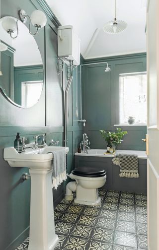 Bathroom with blue painted panelling, patterned tile flooring and traditional fittings