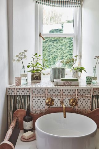 round cloakroom basin on vintage stand with geometric tiles behind