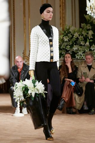 model wearing black leggings and a white jacket in Schiaparelli fall winter 2023