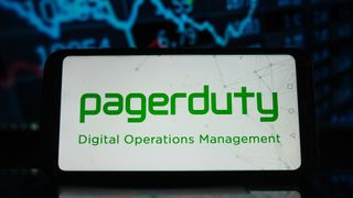 PagerDuty logo and branding pictured on a smartphone screen with stock market graph in the background.