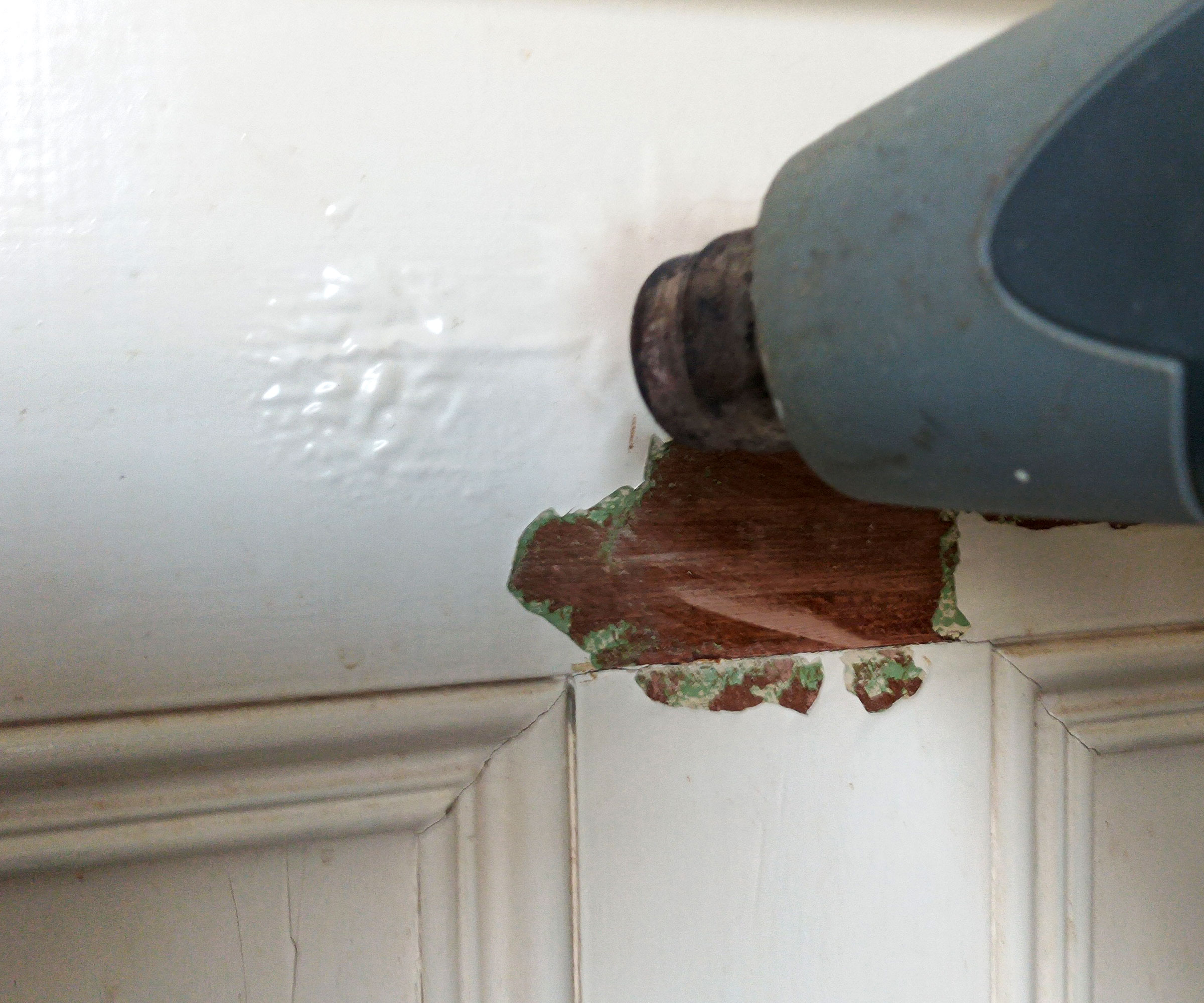 Close up of heat gun blistering white paint on wooden door