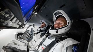 Astronauts in the SpaceX Crew Dragon capsule giving the thumbs-up to the camera