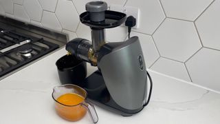 Side view of the Ninja Cold Press Juicer which has been used to juice oranges
